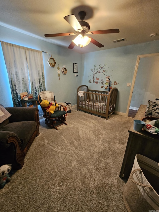 bedroom with carpet floors, a textured ceiling, ceiling fan, and a crib