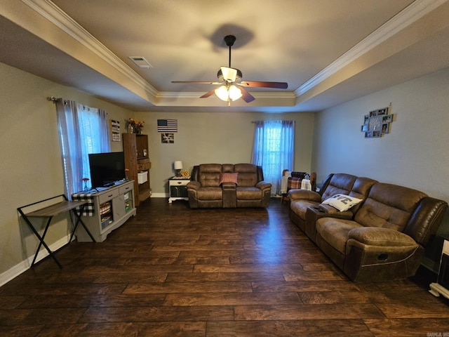 living room with dark wood-type flooring, ceiling fan, ornamental molding, and a raised ceiling