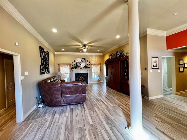 living room featuring a barn door, ceiling fan, light hardwood / wood-style floors, and ornamental molding