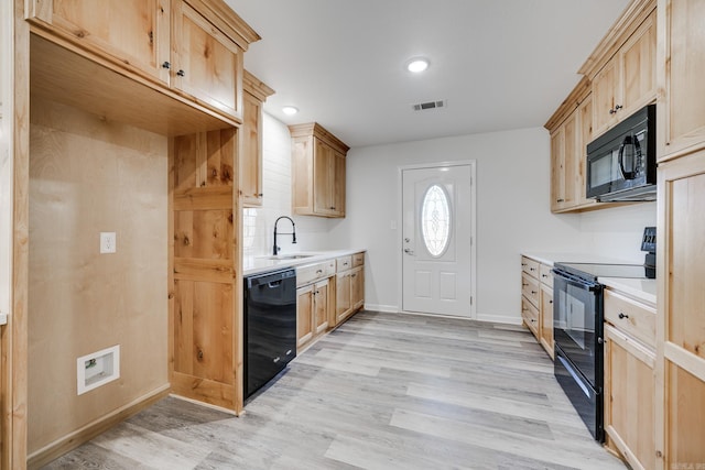 kitchen featuring black appliances, light brown cabinetry, sink, and light hardwood / wood-style floors