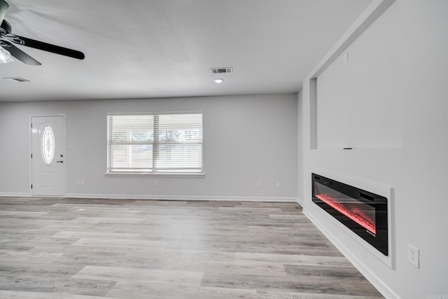 unfurnished living room with ceiling fan, a textured ceiling, and light hardwood / wood-style flooring