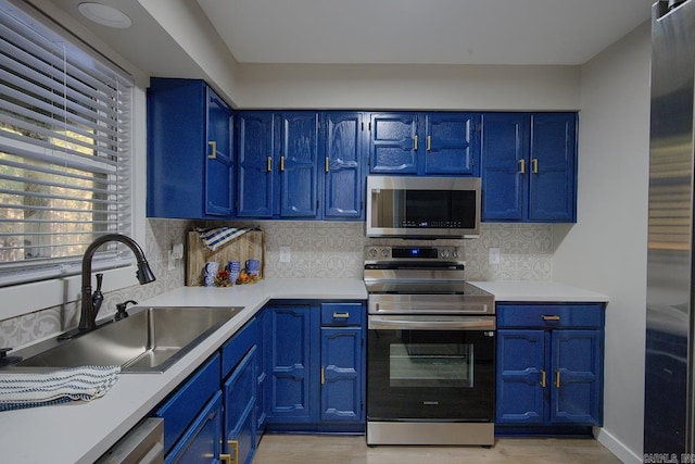 kitchen with tasteful backsplash, blue cabinetry, sink, and stainless steel appliances