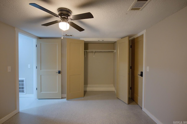 unfurnished bedroom with a textured ceiling, light colored carpet, ceiling fan, and a closet