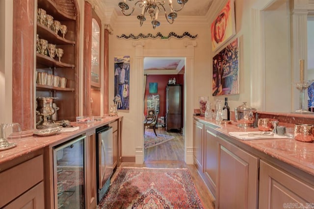 bar featuring ornamental molding, hardwood / wood-style floors, light stone counters, and beverage cooler