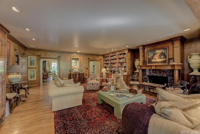 living room featuring ornamental molding, a premium fireplace, and light hardwood / wood-style floors