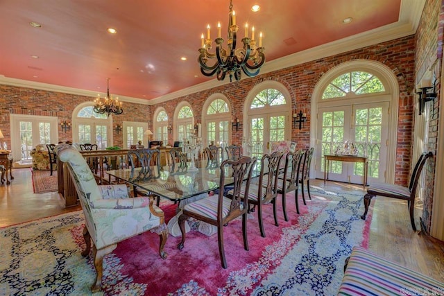 dining room featuring french doors, brick wall, and a chandelier