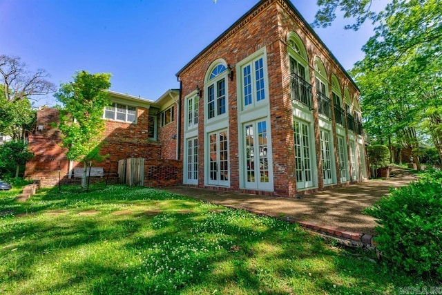 back of property with french doors and a lawn