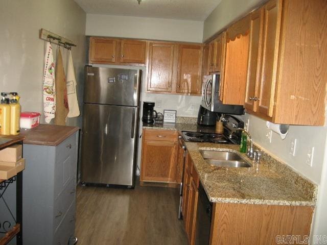 kitchen featuring stainless steel appliances, dark wood-type flooring, sink, and light stone counters