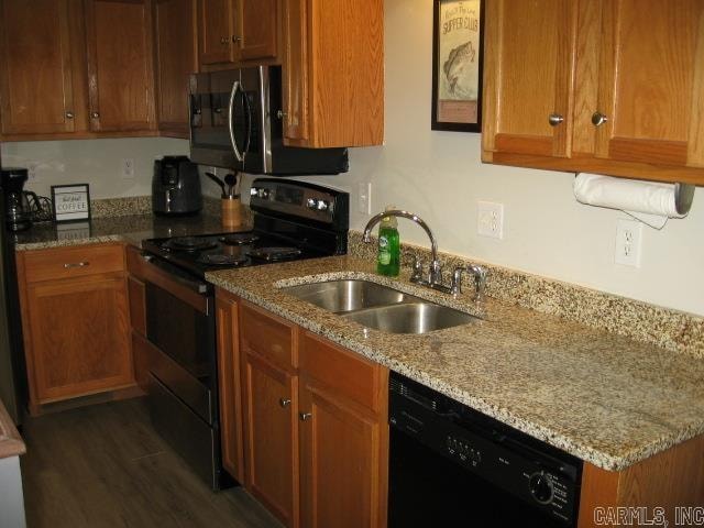 kitchen with dark wood-type flooring, light stone countertops, sink, and black appliances