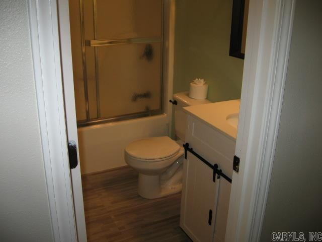 full bathroom with vanity, hardwood / wood-style flooring, toilet, and combined bath / shower with glass door