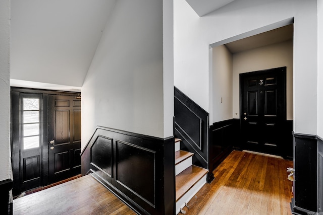 entryway with wood-type flooring and high vaulted ceiling