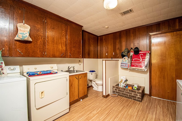 washroom featuring a brick fireplace, separate washer and dryer, wood walls, sink, and light wood-type flooring