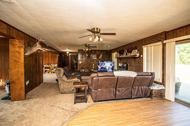 living room featuring light hardwood / wood-style flooring, wood walls, and ceiling fan