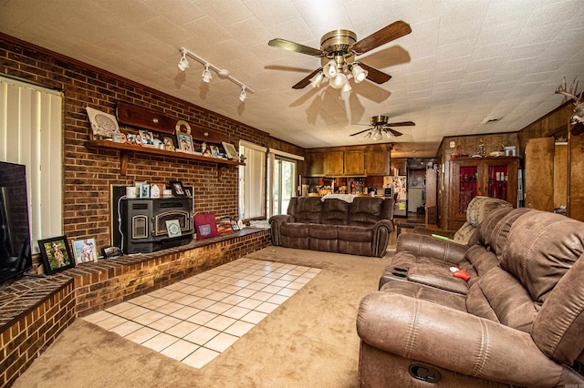 living room featuring carpet, a wood stove, ceiling fan, and brick wall