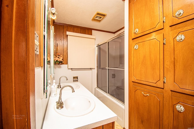 bathroom with enclosed tub / shower combo, vanity, and ornamental molding