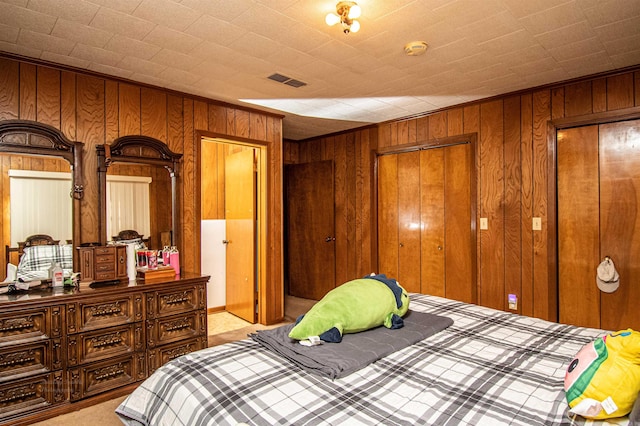 carpeted bedroom featuring wood walls and a closet