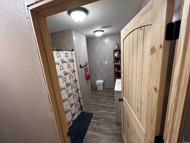 bathroom with toilet, hardwood / wood-style floors, a textured ceiling, wooden walls, and vanity