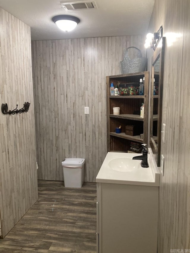 bathroom with wood walls, hardwood / wood-style floors, vanity, and toilet