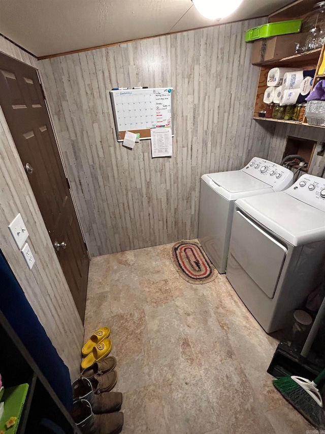 clothes washing area with wooden walls and independent washer and dryer