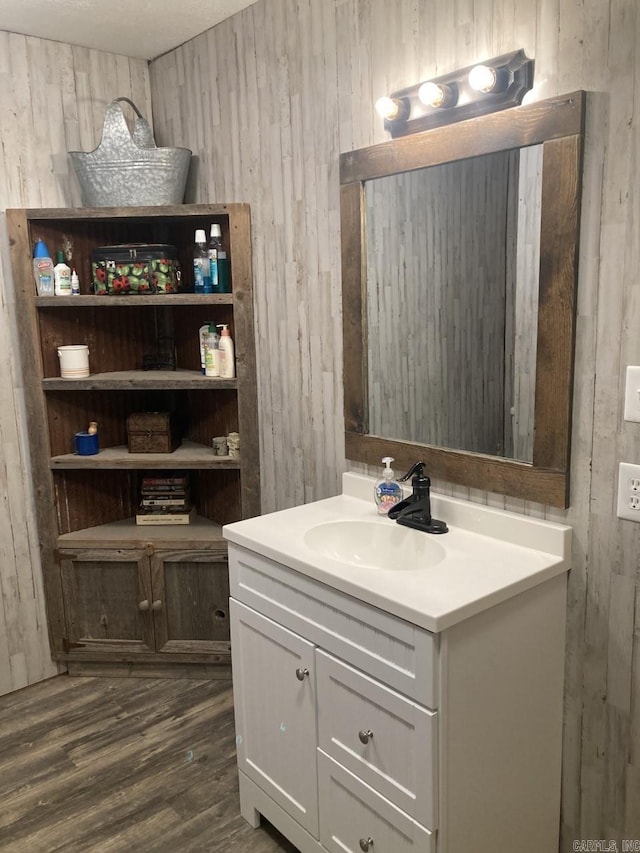 bathroom with wood walls, vanity, and wood-type flooring