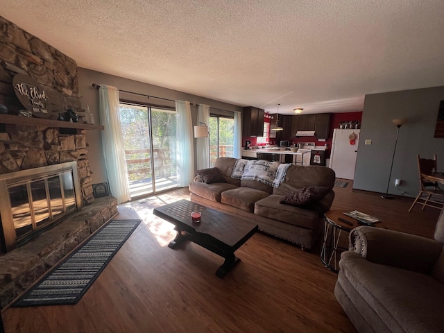 living room featuring dark hardwood / wood-style flooring, a textured ceiling, and a fireplace