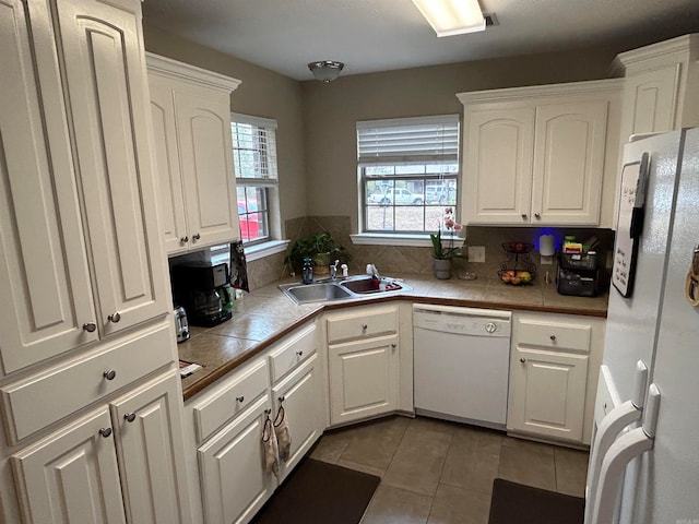 kitchen with tile countertops, white appliances, sink, and white cabinets