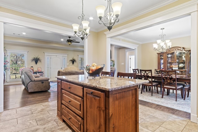 kitchen with a center island, light wood-type flooring, crown molding, and decorative light fixtures