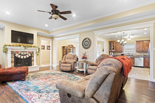 living room with ceiling fan with notable chandelier, light hardwood / wood-style flooring, and crown molding