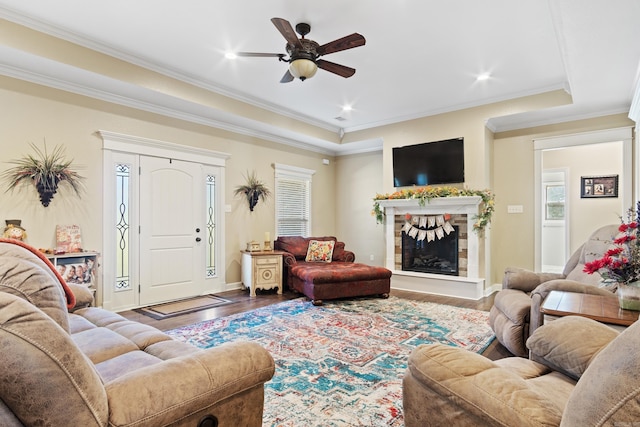 living room with hardwood / wood-style flooring, ceiling fan, crown molding, and a tray ceiling