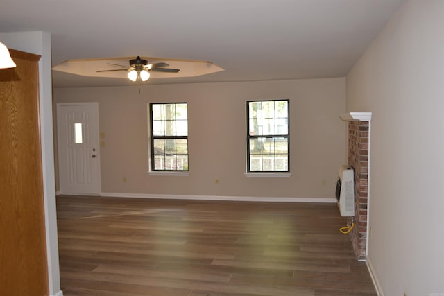 unfurnished living room with a fireplace, ceiling fan, heating unit, and dark hardwood / wood-style flooring