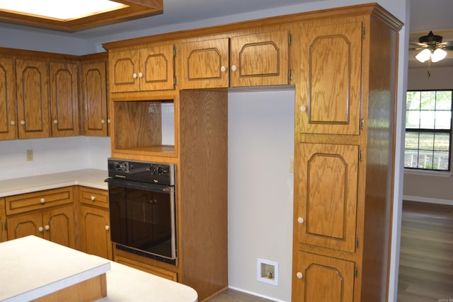 kitchen featuring black oven, wood-type flooring, and ceiling fan