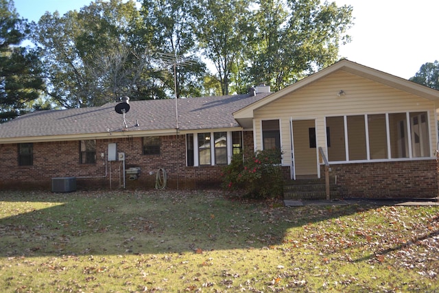 view of front of home featuring central AC unit, a sunroom, and a front lawn