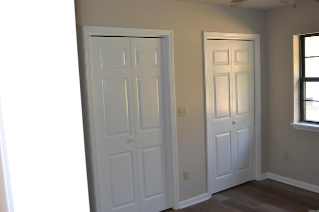 unfurnished bedroom featuring dark wood-type flooring and two closets