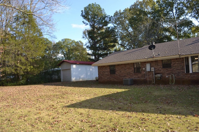 exterior space with a garage, an outdoor structure, cooling unit, and a lawn