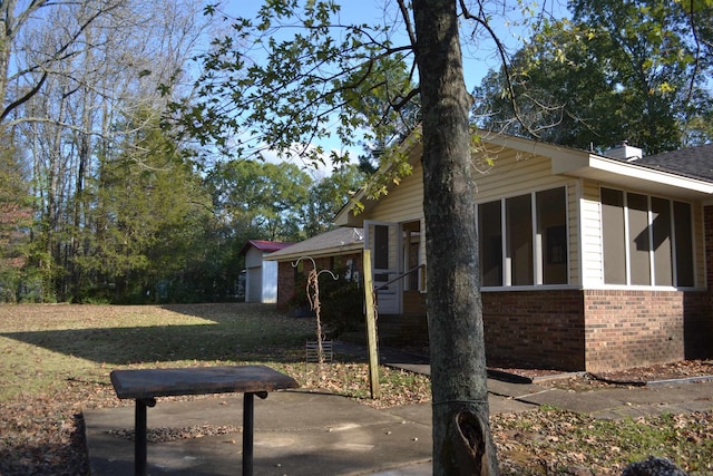 view of home's exterior featuring a sunroom and a yard