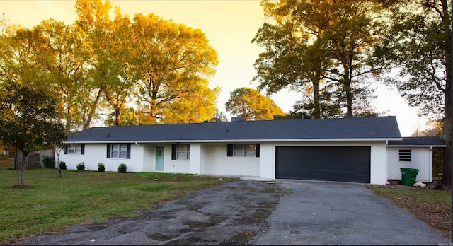 single story home featuring a garage and a yard