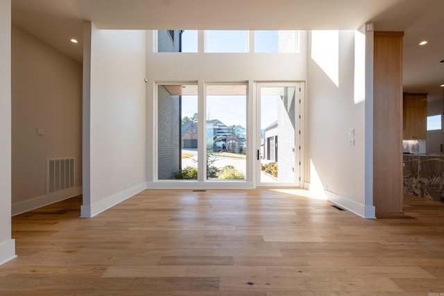 unfurnished room with a high ceiling and light hardwood / wood-style flooring