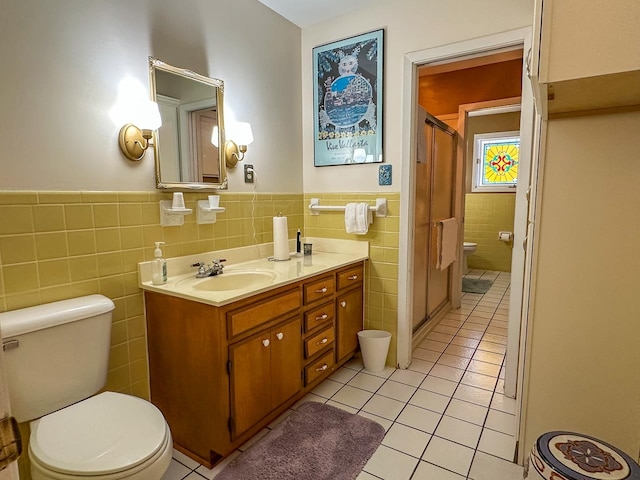 bathroom with toilet, vanity, tile walls, and tile patterned floors