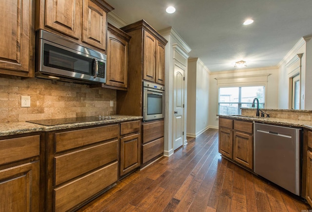 kitchen with sink, stainless steel appliances, light stone counters, dark hardwood / wood-style floors, and crown molding