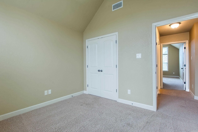 unfurnished bedroom with light colored carpet, vaulted ceiling, and a closet