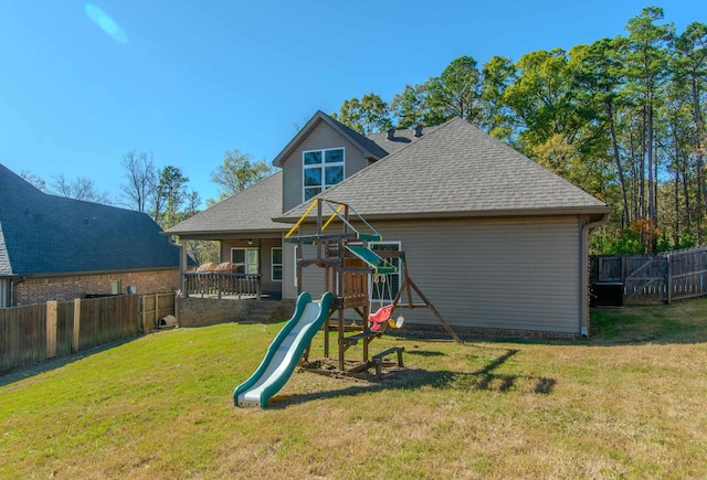 rear view of property with a playground and a yard