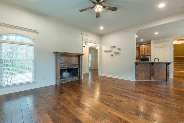 unfurnished living room with crown molding, ceiling fan, and dark wood-type flooring