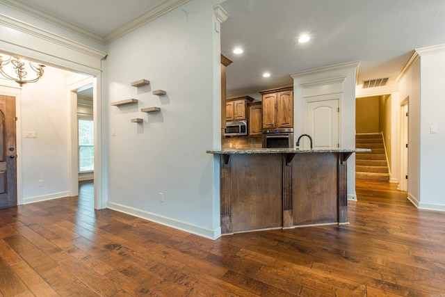 kitchen featuring a kitchen breakfast bar, ornamental molding, stainless steel appliances, stone counters, and dark hardwood / wood-style floors