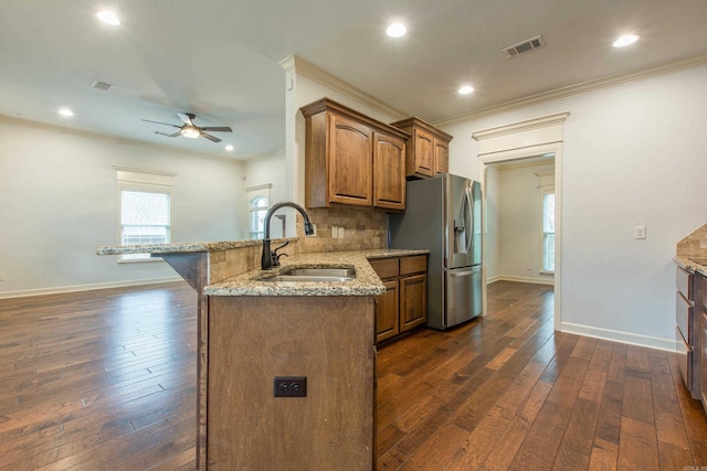 kitchen with sink, dark hardwood / wood-style floors, stainless steel fridge, light stone counters, and kitchen peninsula