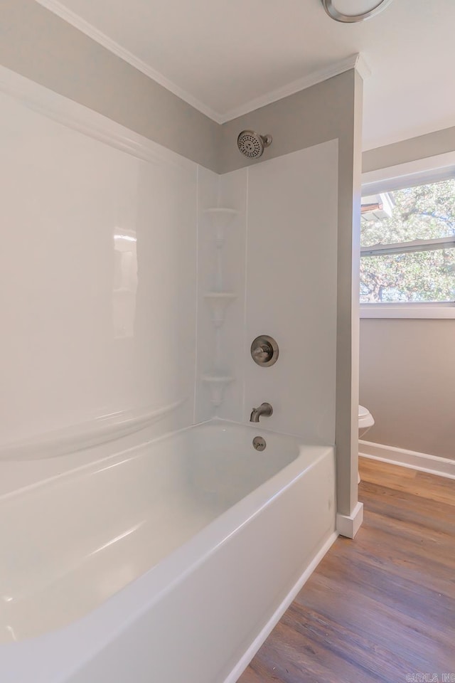 bathroom with toilet, shower / bathtub combination, hardwood / wood-style flooring, and crown molding