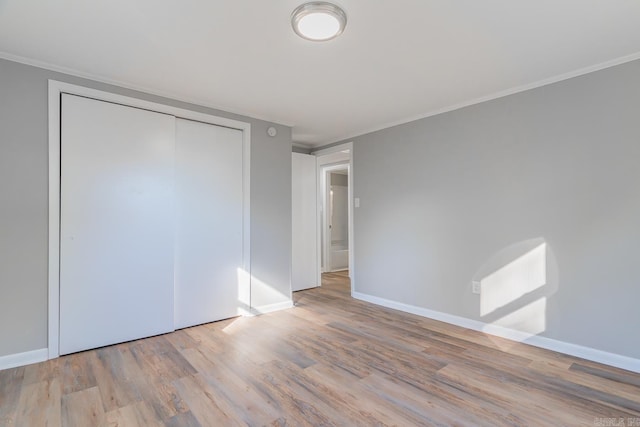 unfurnished bedroom featuring ornamental molding, light hardwood / wood-style floors, and a closet