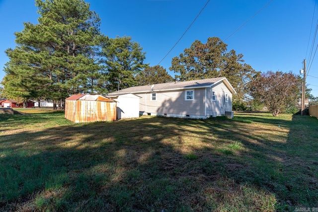 rear view of house with a shed and a lawn