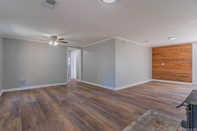 spare room with ornamental molding, dark hardwood / wood-style flooring, wood walls, and ceiling fan