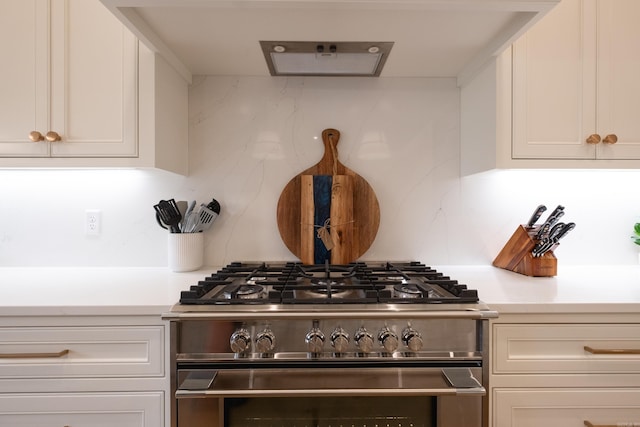 kitchen featuring backsplash, white cabinetry, and gas range