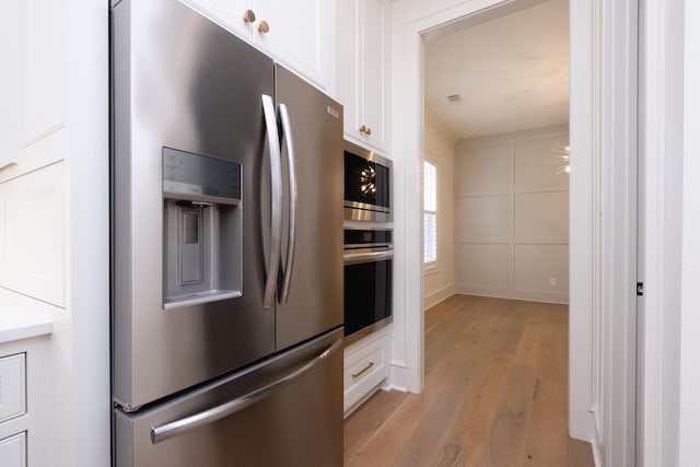 kitchen with white cabinetry, appliances with stainless steel finishes, and light hardwood / wood-style floors